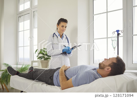 Nurse questions male patient about his symptoms and completes medical history. 128171094