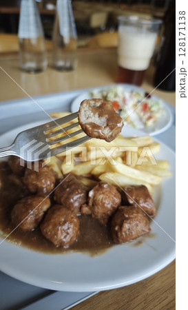 Swedish meatballs with gravy served with French fries and fresh salad on a white plate. This image represents a classic comfort food and traditional dining concept Swedish meatballs with gravy served with French fries and fresh salad on a white plate. This image represents a classic comfort food and traditional dining concept 128171138