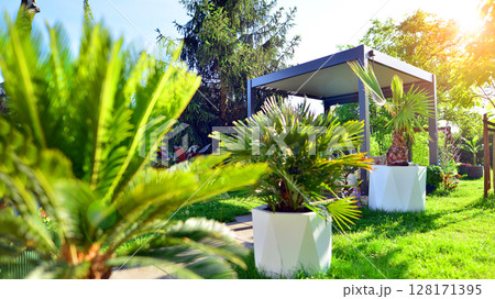 Modern aluminum pergola with stylish garden furniture in a beautiful garden. Modern aluminum pergola with stylish garden furniture in a beautiful garden. 128171395