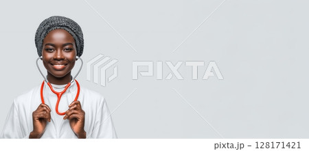A smiling female healthcare professional is depicted, proudly holding a stethoscope in her hands 128171421