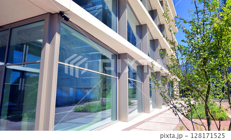 City life, urban landscape and ecology.  Modern office complex with glass facades and smooth lines against backdrop of green trees, concept of modern architecture. Organically building into nature.   128171525
