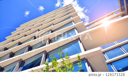 City life, urban landscape and ecology.  Modern office complex with glass facades and smooth lines against backdrop of green trees, concept of modern architecture. Organically building into nature.   128171528