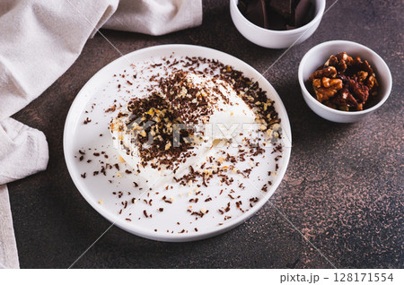 Ice cream bar with chocolate and nuts on a plate on a table Ice cream bar with chocolate and nuts on a plate on a table 128171554