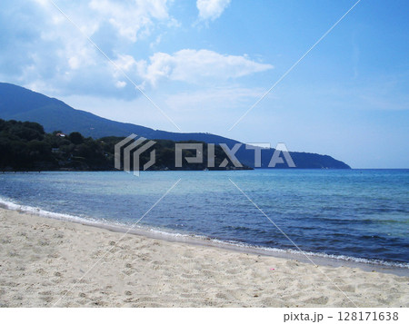 Stunning beach view on Elba Island, Italy, showcasing crystal-clear turquoise waters, golden sand, and lush Mediterranean vegetation. The peaceful shoreline, framed by gentle waves and rocky outcrops 128171638