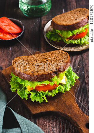 Light sandwich with vegetables and cheese on rye bread on a board on the table vertical view Light sandwich with vegetables and cheese on rye bread on a board on the table vertical view 128171670