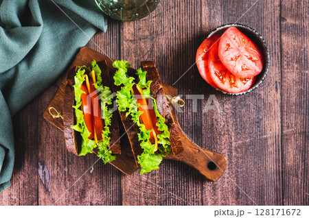 Vegetarian sandwich with tomato, cheese and lettuce on a board on a table top view 128171672