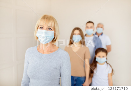 Senior woman in face mask waiting in line for vaccine against coronavirus at hospital, empty space. Mature female patient standing in queue for population covid-19 immunization 128171710