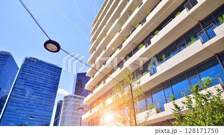 City life, urban landscape and ecology.  Modern office complex with glass facades and smooth lines against backdrop of green trees, concept of modern architecture. Organically building into nature.   128171750