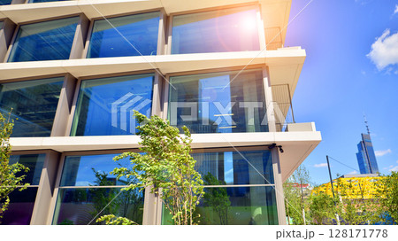 City life, urban landscape and ecology. Modern office complex with glass facades and smooth lines against backdrop of green trees, concept of modern architecture. Organically building into nature. City life, urban landscape and ecology. Modern office complex with glass facades and smooth lines against backdrop of green trees, concept of modern architecture. Organically building into nature. 128171778