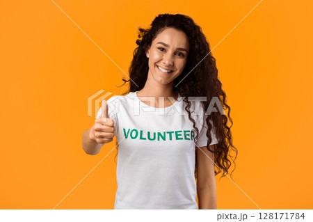Volunteer Woman Showing Like Gesturing Thumbs Up Standing On Yellow Studio Background, Smiling To Camera. I Approve Charity Work And Volunteering Concept Volunteer Woman Showing Like Gesturing Thumbs Up Standing On Yellow Studio Background, Smiling To Camera. I Approve Charity Work And Volunteering Concept 128171784