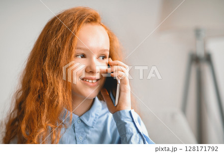Phone Talk And Communication Concept. Closeup portrait of cheerful casual red-haired female kid making call using smartphone, teenager talking to parents or friends, enjoying conversation 128171792