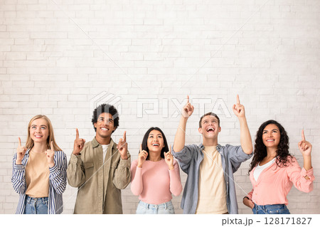 Amazing offer, great news and free space for text and ad. Surprised happy young international students show thumbs up and ready to study at university, on white wall background, studio shot, square 128171827