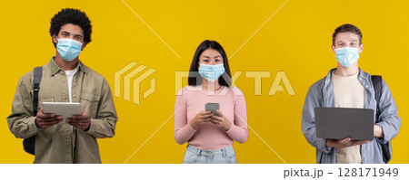 Remote education and social distance and new normal during covid-19 lockdown. Teen asian, african american and european students in protective masks read in devices, isolated on orange background 128171949