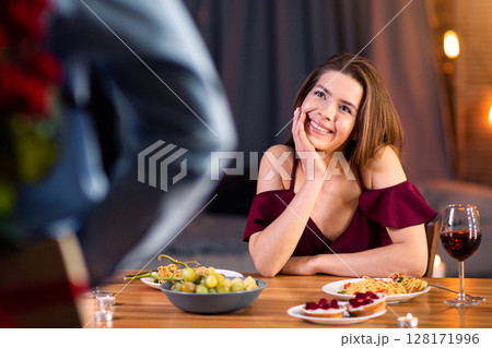 Man Making Romantic Surprise To His Girlfriend In Restaurant, Holding Bunch Of Red Roses And Gift Behind Back. Happy Young Couple Dining Together At Valentine's Day, Selective Focus On Woman 128171996