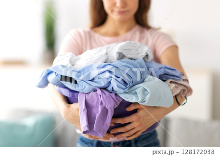 Unhappy millennial housewife with pile of clothes sick and tires of washing or ironing at home, selective focus. Young woman exhausted by domestic chores and household duties, closeup 128172038