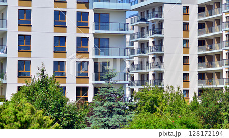 European residential architecture harmonizing with nature. Eco-friendly living in city with greens. Eco apartment building saving energy and fresh air concept. European residential architecture harmonizing with nature. Eco-friendly living in city with greens. Eco apartment building saving energy and fresh air concept. 128172194