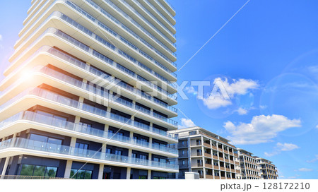 Exterior of a high modern multi-story apartment building - facade, windows and balconies. Modern glass balcony railings. Exterior of a high modern multi-story apartment building - facade, windows and balconies. Modern glass balcony railings. 128172210