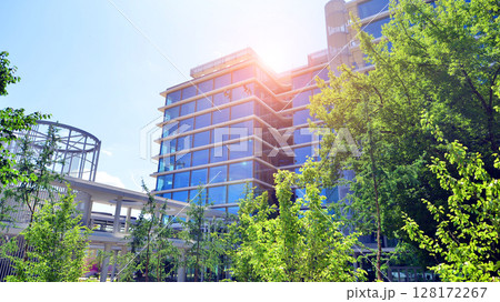 Sustainable glass office building with trees for reducing carbon dioxide. Eco-friendly building in modern city. Office with green environment. Corporate building reduce CO2. 128172267