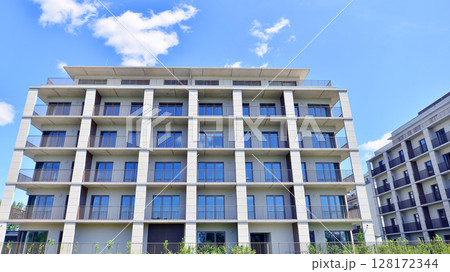 Modern apartment buildings on a sunny day with a blue sky. Facade of a modern apartment building. Modern residential apartment building complex condo. 128172344