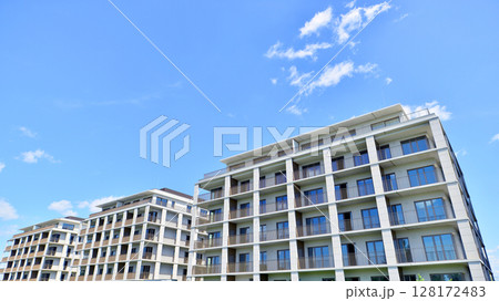 Modern apartment buildings on a sunny day with a blue sky. Facade of a modern apartment building. Modern residential apartment building complex condo. 128172483