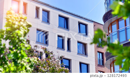 European residential architecture harmonizing with nature. Eco-friendly living in city with greens. Eco apartment building saving energy and fresh air concept.  128172493