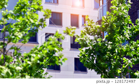 European residential architecture harmonizing with nature. Eco-friendly living in city with greens. Eco apartment building saving energy and fresh air concept.  128172497