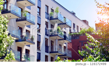 European residential architecture harmonizing with nature. Eco-friendly living in city with greens. Eco apartment building saving energy and fresh air concept.  128172499