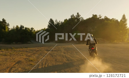 Man, professional motorcyclist in full moto equipment riding crops enduro bike on mountain road at sunset. Concept of motosport, speed, hobby, journey, activity 128172721