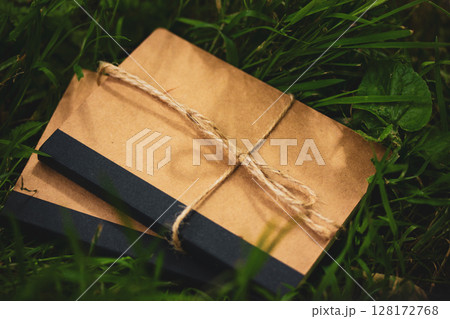 Kraft vintage natural simple brown cardboard notebooks lie on green grass top view. Goods for school and learning. Ecological ribboned paper diaries. Kraft vintage natural simple brown cardboard notebooks lie on green grass top view. Goods for school and learning. Ecological ribboned paper diaries. 128172768