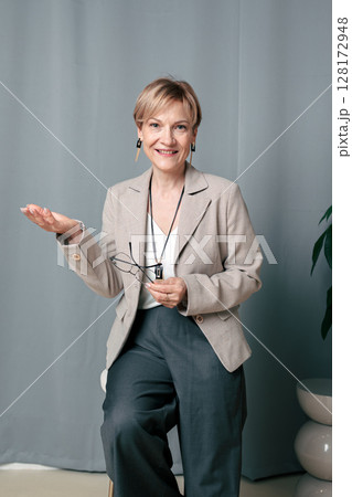 Portrait of happy woman. Confident, successful mature woman on light gray background. Looking at camera. High quality photo Portrait of happy woman. Confident, successful mature woman on light gray background. Looking at camera. High quality photo 128172948