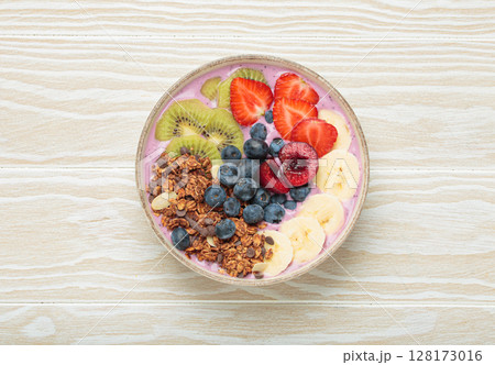 Delicious acai bowl with fresh fruits and granola in white ceramic bowl on white wooden table top view, healthy breakfast or snack Delicious acai bowl with fresh fruits and granola in white ceramic bowl on white wooden table top view, healthy breakfast or snack 128173016