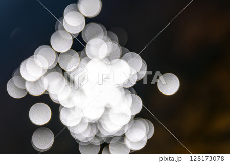 Delicate white light bokeh shapes gently blurred against a dark background, 128173078