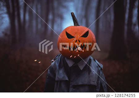 Spooky figure with pumpkin head smoking with smoke and sparks Spooky figure with pumpkin head smoking with smoke and sparks 128174255