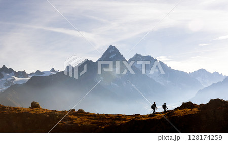 Two hikers walking above Lac de Cheserys in the French Alps Two hikers walking above Lac de Cheserys in the French Alps 128174259