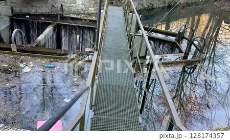 Bridges and Reflective Water Surfaces Captured in an Abandoned Industrial Location Setting Bridges and Reflective Water Surfaces Captured in an Abandoned Industrial Location Setting 128174357