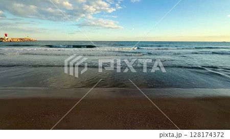 Experience the beautiful ambiance of serene beach waves at sunset, where nature meets tranquility 128174372