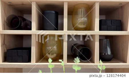 Stylish Glasses and Containers Expertly Organized on a Beautiful Wooden Shelf Display Stylish Glasses and Containers Expertly Organized on a Beautiful Wooden Shelf Display 128174404