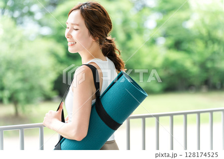 ストレス解消・リフレッシュに公園でヨガをする女性・ヨガマット 128174525