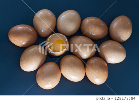 View of Egg yolk in Broken raw chicken eggshell in the among of Fresh chicken egg (Hen egg) on dark background. View of Egg yolk in Broken raw chicken eggshell in the among of Fresh chicken egg (Hen egg) on dark background. 128175584