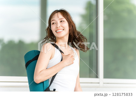 ヨガマットを持った健康的な女性(ヨガ講師・ヨギーニ) ヨガマットを持った健康的な女性(ヨガ講師・ヨギーニ) 128175833