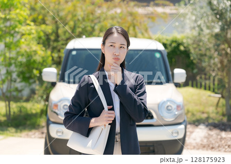 車の前で悩む表情の女性 128175923