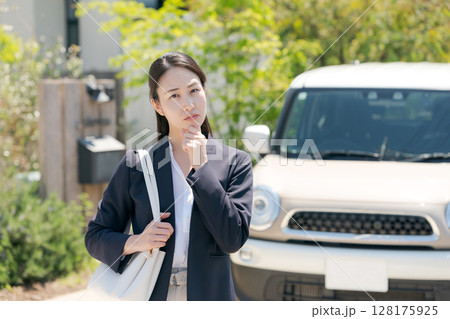 車の前で悩む表情の女性 128175925