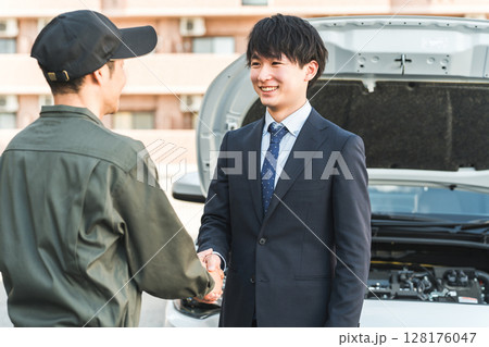 ロードサービスを受けて整備士と握手するドライバーの若い男性 128176047