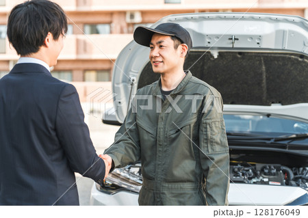 ロードサービスに派遣されてドライバーに感謝されるロードアシストスタッフの男性作業員 128176049