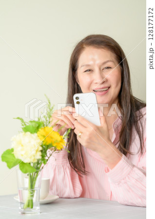 座ってスマホを使うシニア女性 128177172