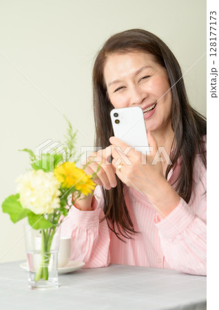 座ってスマホを使うシニア女性 座ってスマホを使うシニア女性 128177173