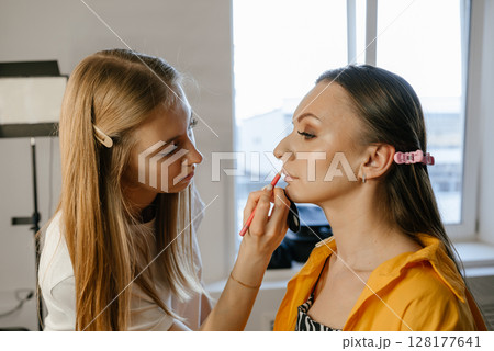 Makeup Artist Applying Lipstick to Model in Studio Makeup Artist Applying Lipstick to Model in Studio 128177641