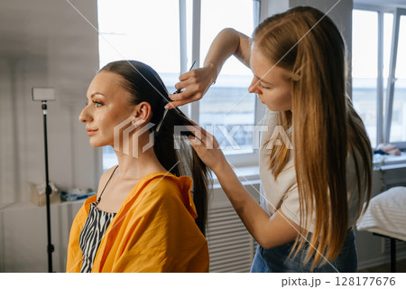 Hairdresser Styling Woman's Long Hair in Salon Hairdresser Styling Woman's Long Hair in Salon 128177676