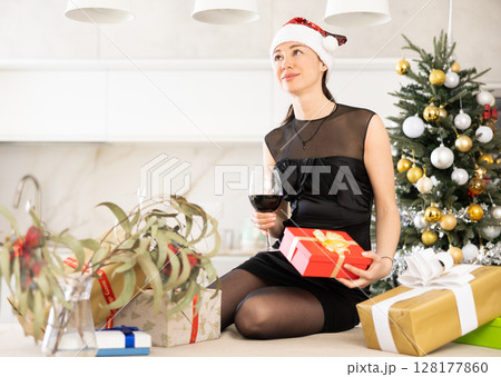 girl holds box with gift and glass of wine. She dreams of new year holiday. 128177860
