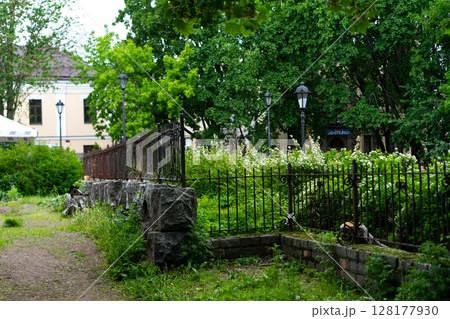 Tranquil Park Pathway With Greenery and Decorative Iron Fence 128177930